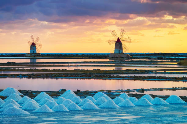 pôr do sol na lagoa de sal evoporation em marsala sicília contra moinhos de vento - trapani - fotografias e filmes do acervo