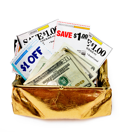 Vertical shot of an open gold metallic purse stuffed with coupons and folded five and twenty dollar bills.  White background.