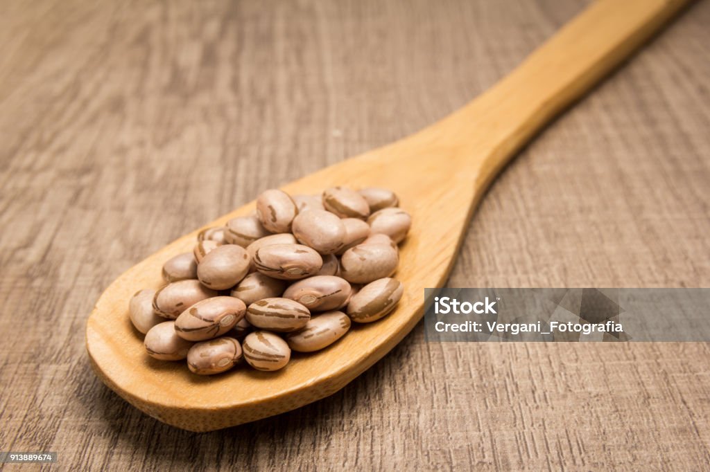 Feijão pinto vegetal. Colher e grãos sobre a mesa de madeira. - Foto de stock de Agricultura royalty-free