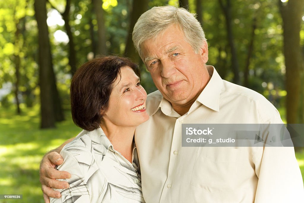 Senior feliz pareja atractiva en el parque abrazar - Foto de stock de Abrazar libre de derechos