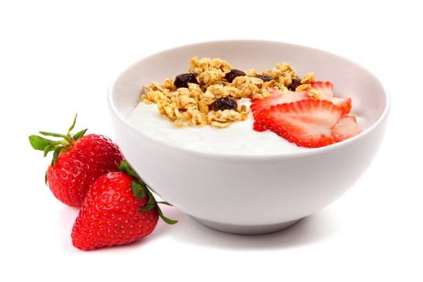 Bowl of yogurt with strawberries & granola, isolated on white Yogurt with strawberries and granola in a white bowl. Side view, with berries isolated on a white background. greek yogurt photos stock pictures, royalty-free photos & images
