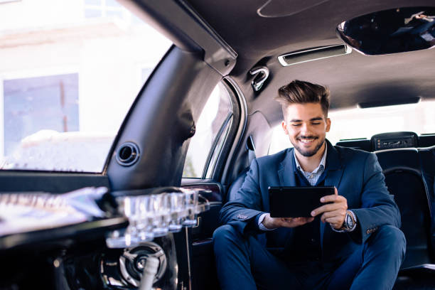 istock Businessman is looking at tablet and smiling in limo 913908982