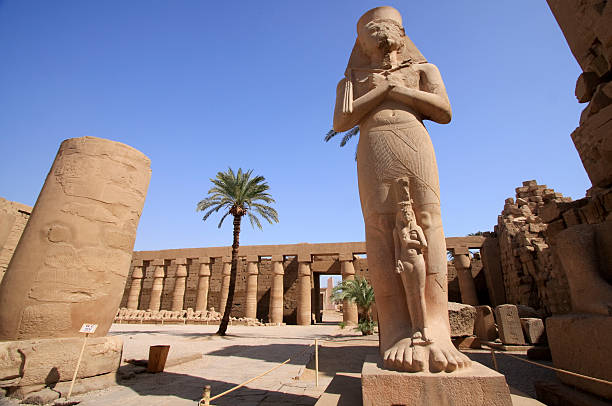 A large beautiful stone statue of a black proud majestic pharaoh in a golden cap, a crown in the shape of a jug against a blue sky in Egypt.