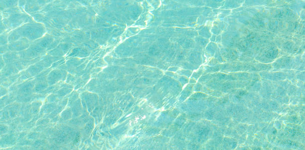 istock Swimming pool blue water with a wave and sunlight reflection 913922096
