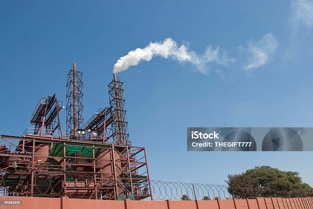 Industrial Smoking Chimney Pollution Industrial Chimney seen polluting smoke against a bright blue sky.. Cement Factory Stock Photo