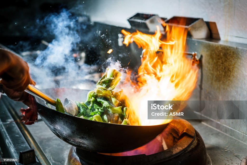 Chef-kok in de keuken van het restaurant bij kachel met hoge brandende vlammen - Royalty-free Kok Stockfoto