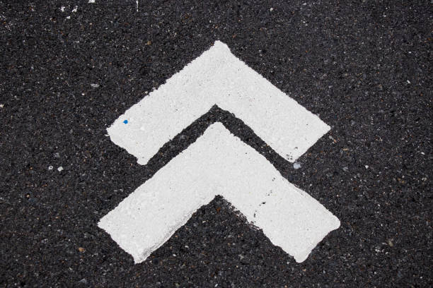 istock White painting in forward direction arrow symbol on black asphalt road background 913965444