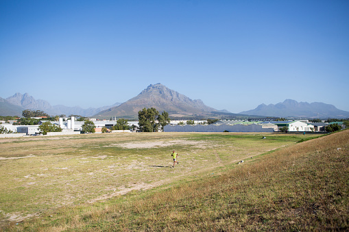 A black male runs across the local sports field in his township near Stellenbosch where he lives