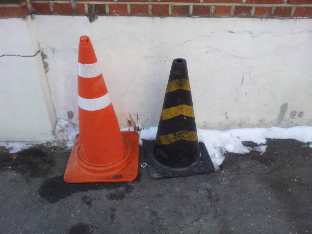 Traffic cones with yellow & grey strips and white & orange  strips placed on grey asphalt, Road construction warning cone