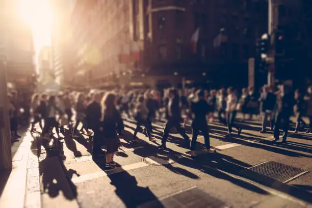 Crowd of people walking over the crosswalk at sunset. Sydney, Australia