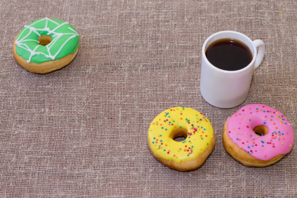istock Donuts with icing on the table. Nearby is a mug with coffee. Sweet colored donuts 913972556