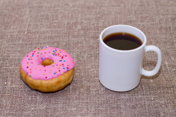 istock Donut with icing on the table. Nearby is a mug with coffee 913972854