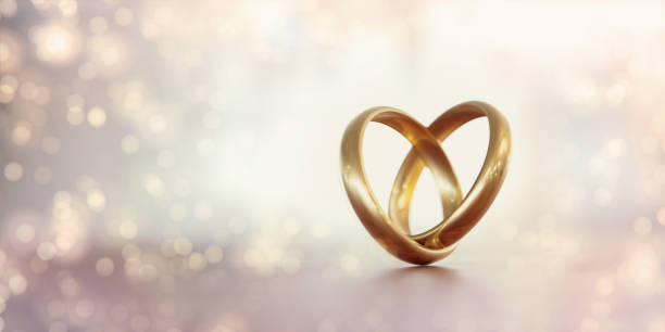 gold wedding rings forming a heart shape over pale background - wedding ring love engagement imagens e fotografias de stock