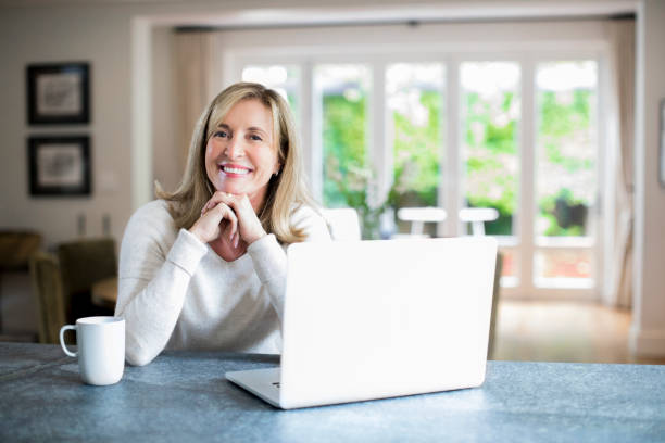 istock Smiling woman with laptop and coffee cup on table 913980014
