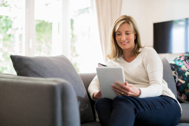 istock Smiling mature woman using digital tablet on sofa 913980232