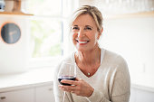 Smiling mature woman holding wineglass in kitchen
