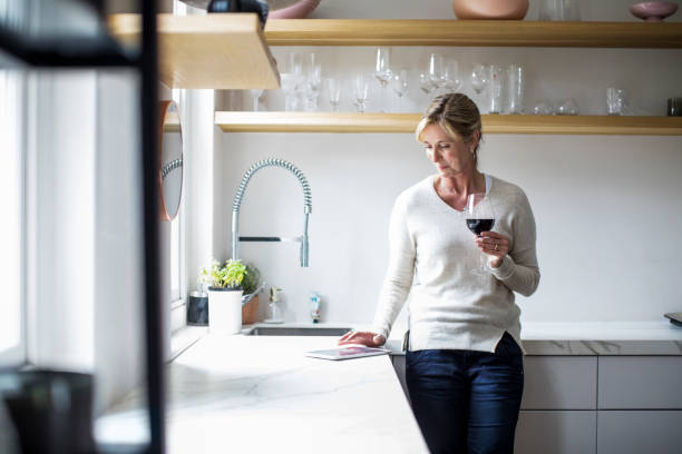 istock Woman with wineglass and tablet PC in kitchen 913980398