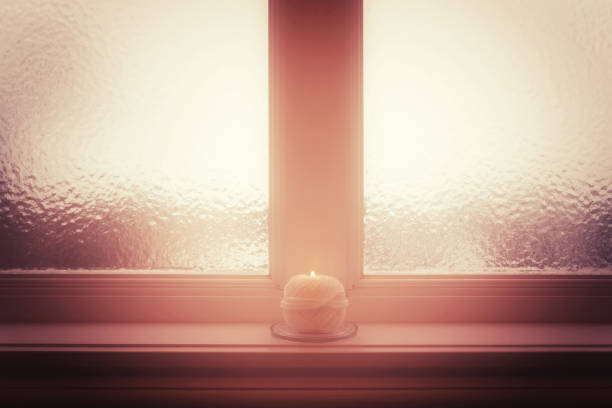 istock Frosted window and burning candle and in misty light 913983772