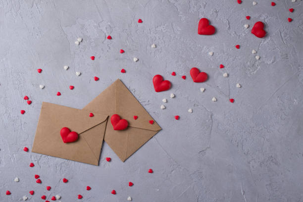 istock Two craft paper postal envelope with multicolor sweet sugar candy hearts. Love message or gift concept. 913987036