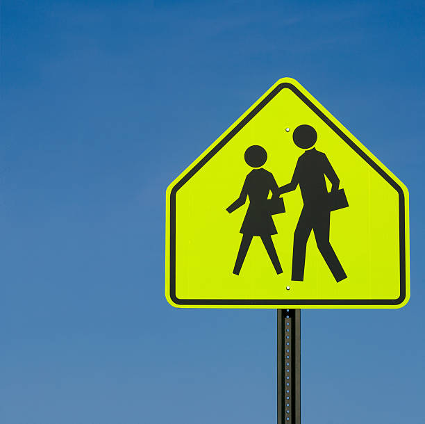 A neon yellow sign indicating an area where children cross for school.