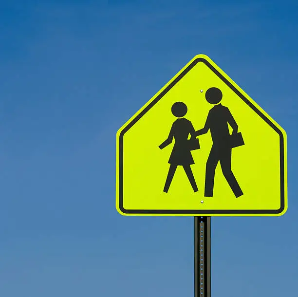 A neon yellow sign indicating an area where children cross for school.