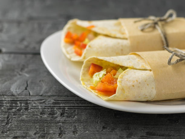 istock Two vegetable roll is Packed in a wrapping paper on a white plate on a wooden table. 913992408