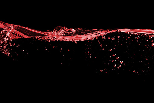 Clear splash surface of red wine or juice water with drops. Isolated on a black
