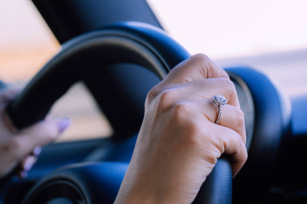 istock Image of female hands on a steering wheel, steadily driving down a road. 913994900
