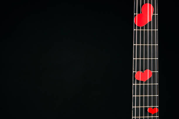 Red hearts on the strings of a acoustic guitar isolated on black background with copy space for text, close-up.Valentine's Day and love music concept. Hearts are a symbol of love.