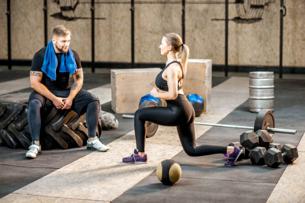 istock Woman squatting with trainer in the gym 914003176