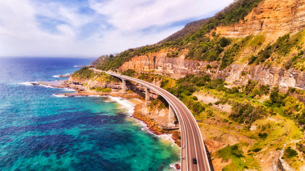 D Sea Cliff Br 2 South Unique Sea Cliff Bridge on the Grand Pacific drive in NSW on a sunny summer day southbound elevated mid-air view over passing car and foot traffic along steep sandstone cliff. clifton stock pictures, royalty-free photos & images