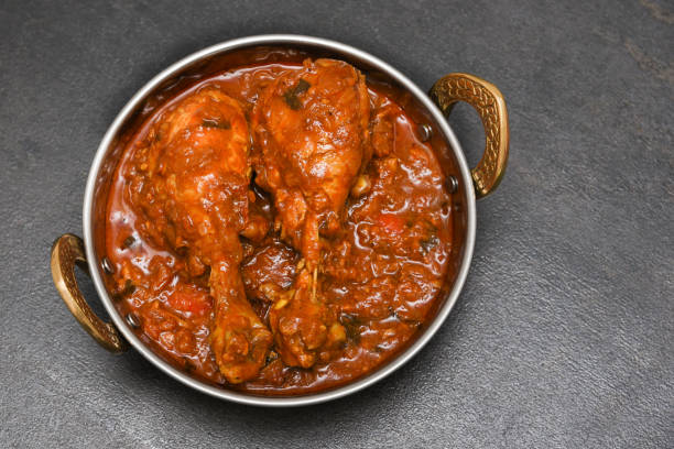 Indian Dish of spicy hot Chicken curry in red Indian spicy chicken curry top view. Traditional kerala chicken curry cooked in thick gravy with herbs and spices. Side dish for appam puttu chapatti parota served in iron or copper bowl with dark black background chicken curry stock pictures, royalty-free photos & images