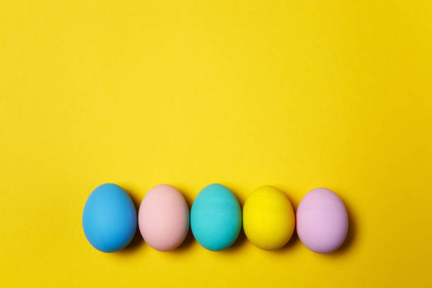 istock Row of five colorful pastel monophonic painted Easter eggs isolated on yellow background for card or postcard. Happy Easter concept. Copy space for advertisement. With place for text. Top view on eggs 914014494