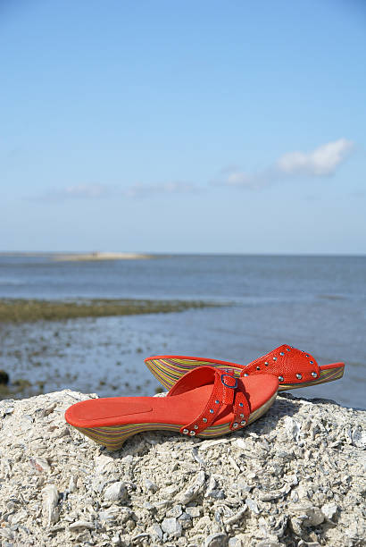 Red shoes on a rock by the water stock photo