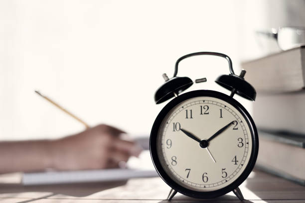 istock Child writing on notebook with retro alarm clock and books on table 914023618