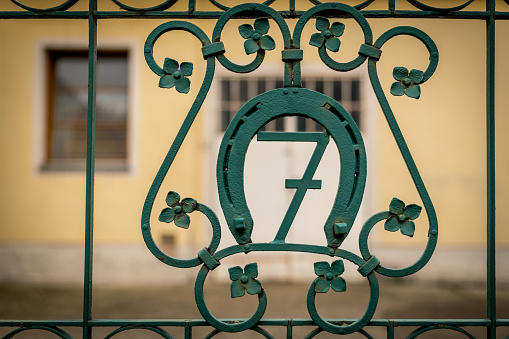 House number seven on a green iron gate, surrounded by a horseshoe