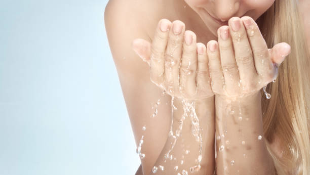 istock Young beautiful woman cleaning her face with water 914030646