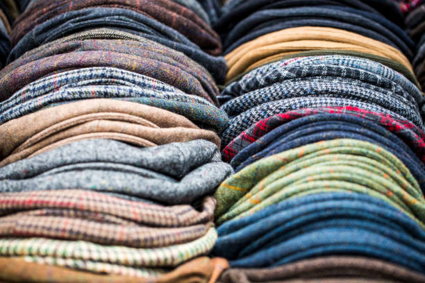 Close up of collection of handmade men's flat caps for sale at clothing market, London, UK Close up color image depicting a vast selection of men's flat caps, of different colors, patterns and designs, in a row and for sale on a market stall at Spitalfields Market in east London, UK. flat cap stock pictures, royalty-free photos & images