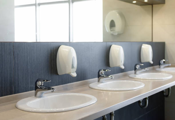 public restroom with sinks faucets and mirror - urinal clean contemporary in a row imagens e fotografias de stock
