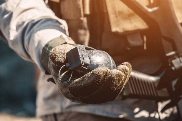 The hand holds an old Soviet grenade on pink background. Closeup photo