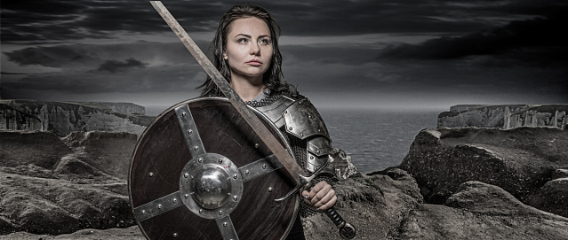 Sword wielding viking warrior dark haired female in wild highland countryside
