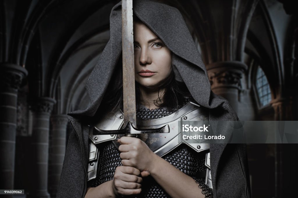 Sword wielding viking warrior dark haired female in wild highland countryside Warrior - Person Stock Photo