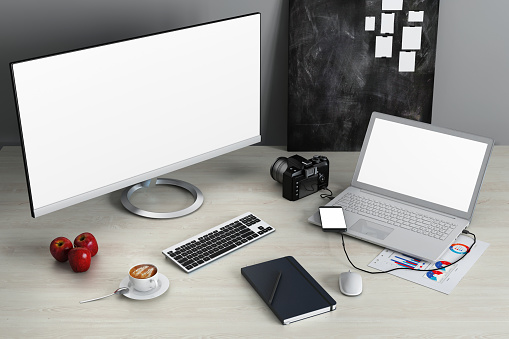 Personal point of view - home office desk with one desktop computer monitor, laptop, smart phone, notepad, coffee and office accessories. Copy space freelance work design template