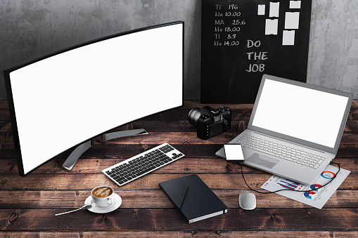 Personal point of view - home office desk with one desktop computer monitor, laptop, smart phone, notepad, coffee and office accessories. Copy space freelance work design template