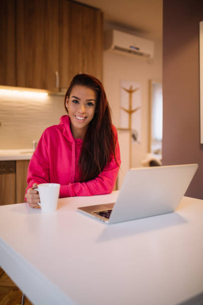istock Young attractive girl drinking coffee at kitchen and checking the internet. 914046118
