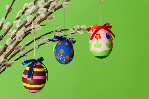 Three colored easter eggs on willow bouquet with pussy willows