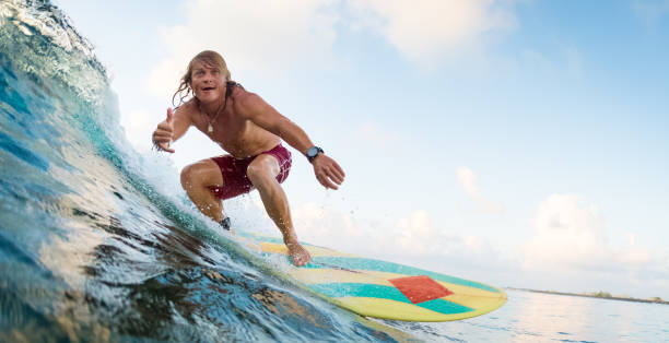 Young man surfer rides the ocean wave
