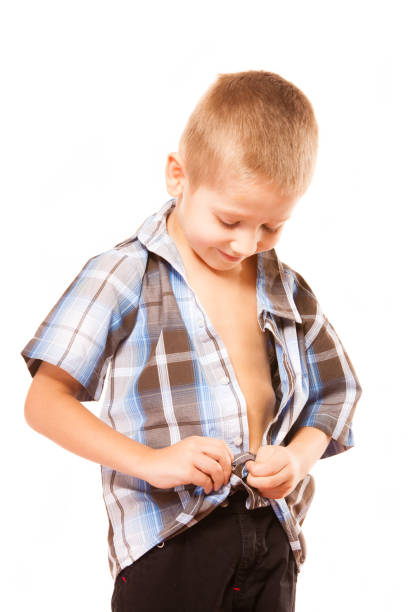 istock little boy buttoning on shirt, isolated on white 914049816