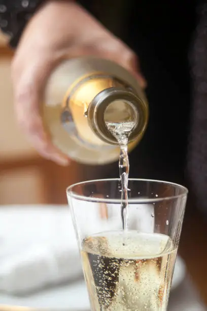 Photo of Pouring white wine, champagne, in wineglass.