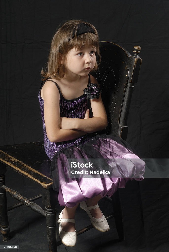 Vestido Menina sentada na cadeira antiga surpreendida olhando para cima - Royalty-free Adulto Foto de stock